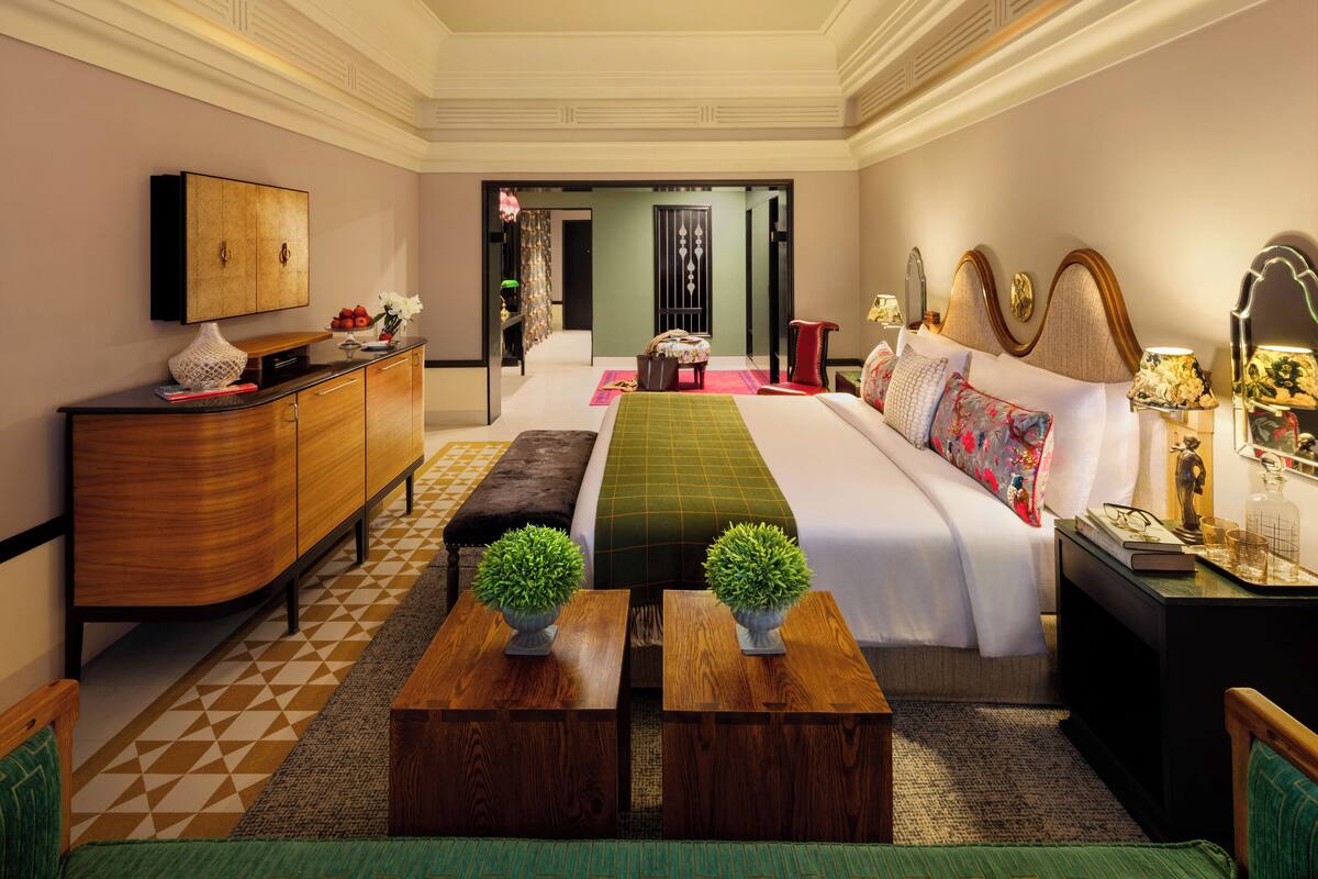 Une chambre d’hôtel avec un grand lit, une commode en bois, une télévision et un bureau avec une lampe.