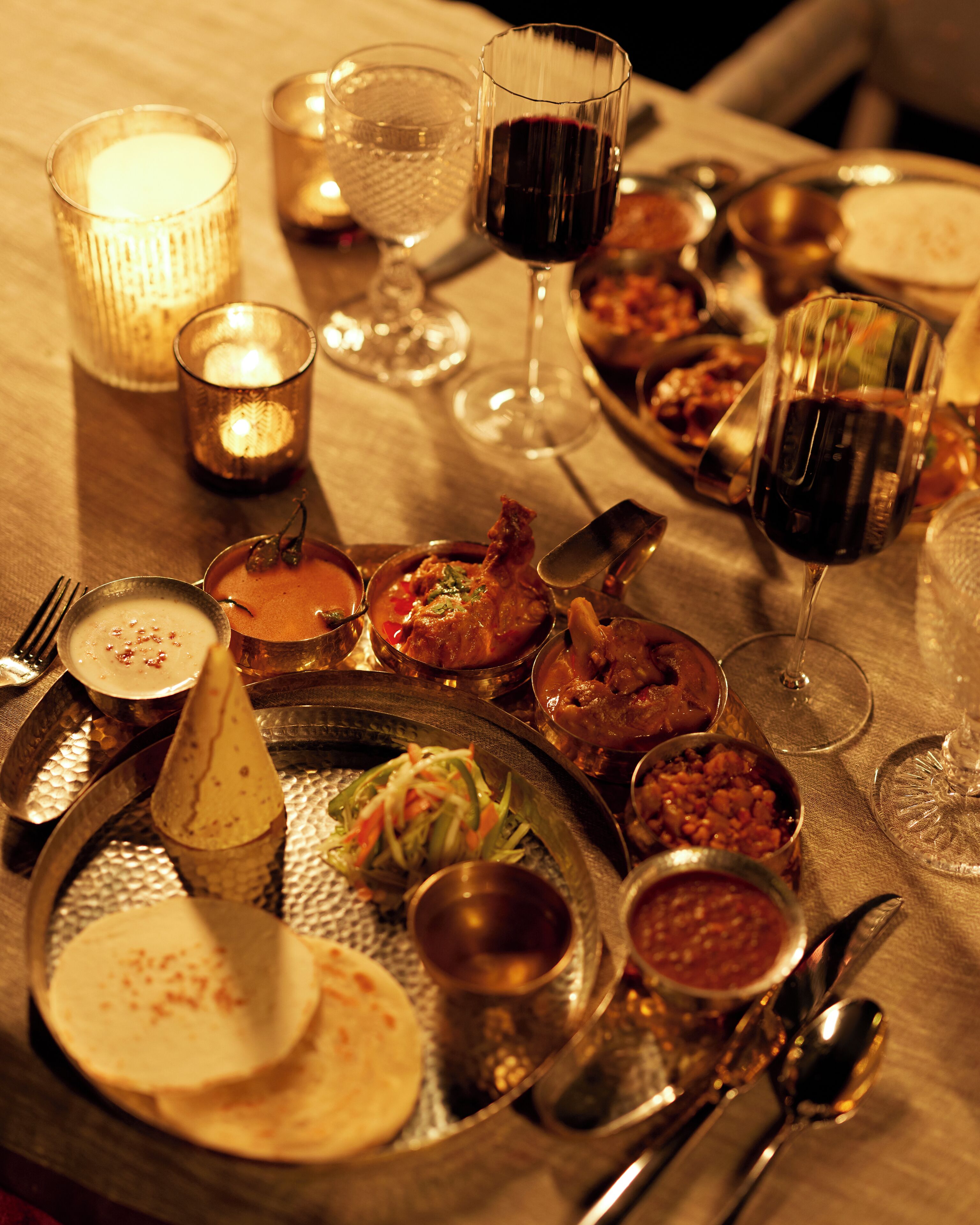 A table set with various dishes, glasses of wine, and a candle.