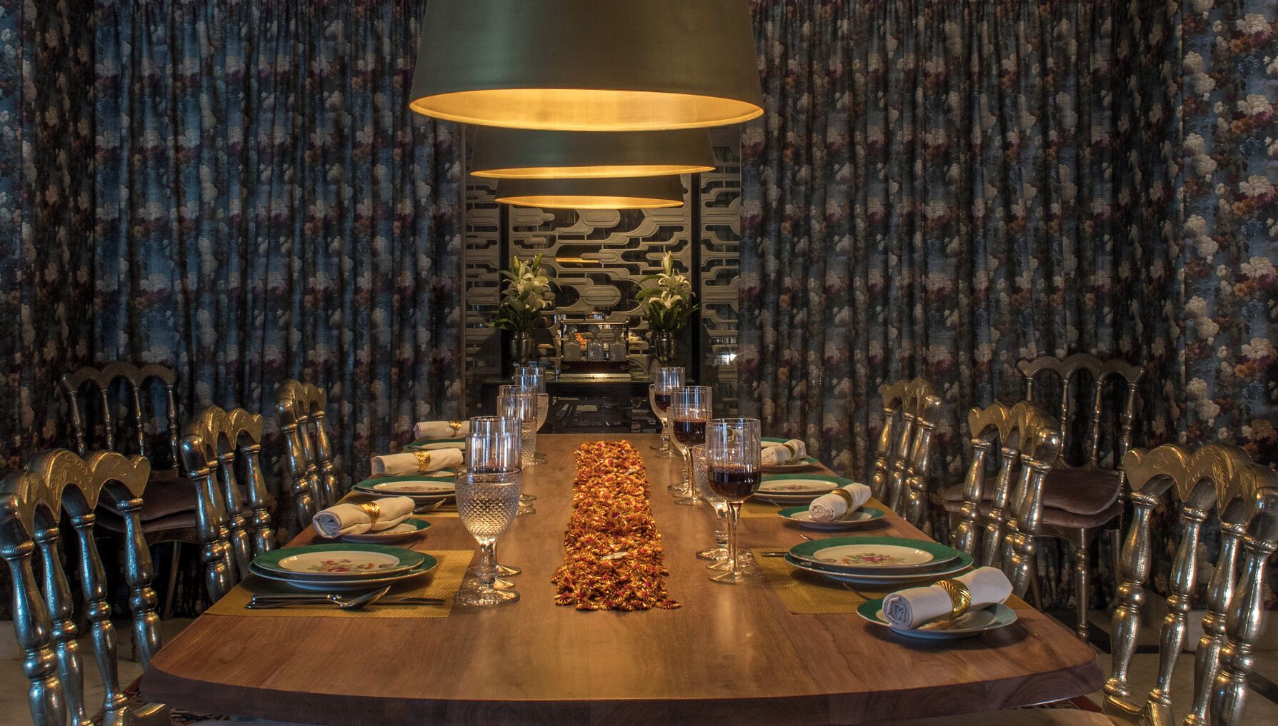 A formal dining room with a long table set for a meal, flanked by ornate chairs, and a decorative centerpiece.