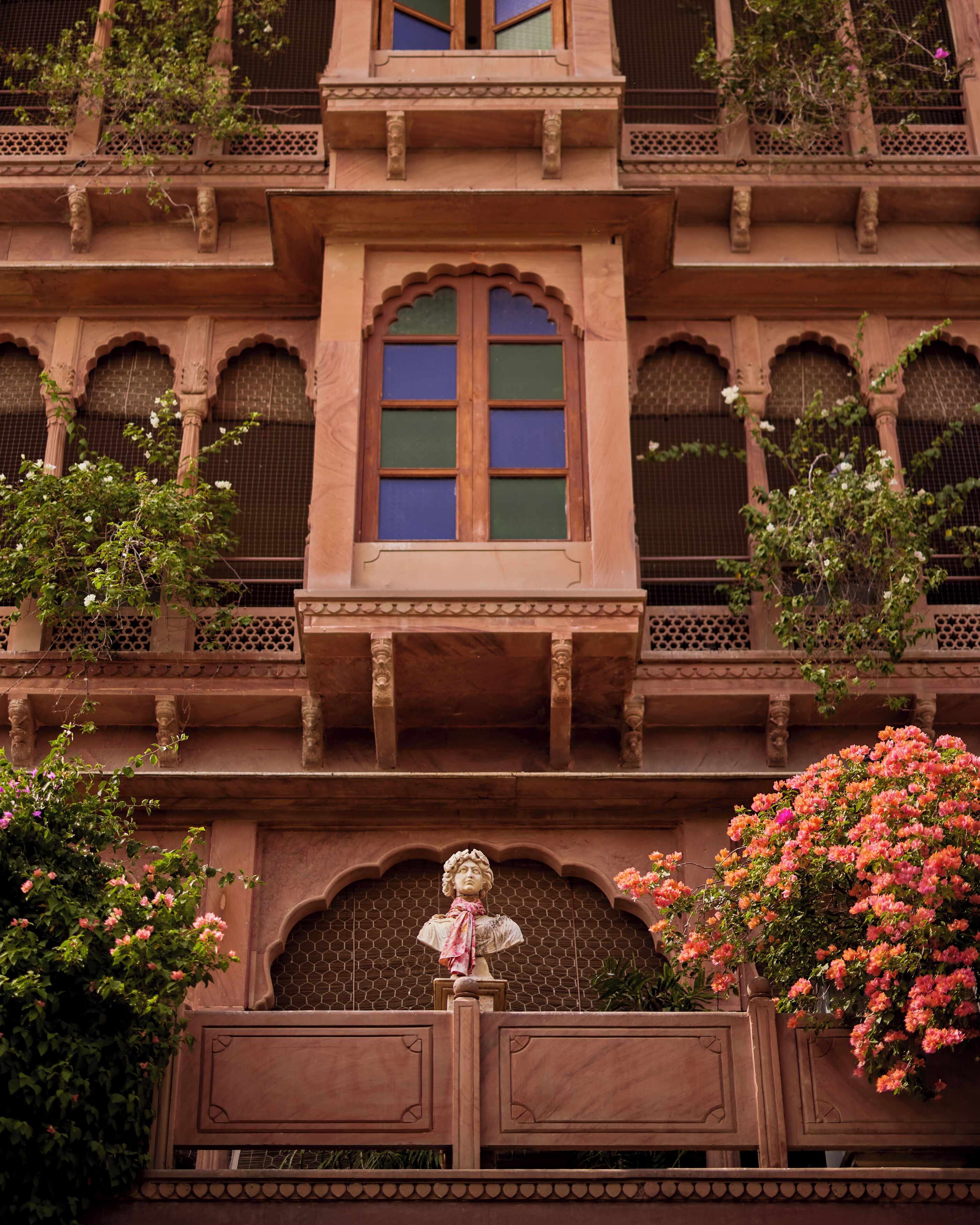 A building with a central arched window, multiple balconies, and decorative stonework.