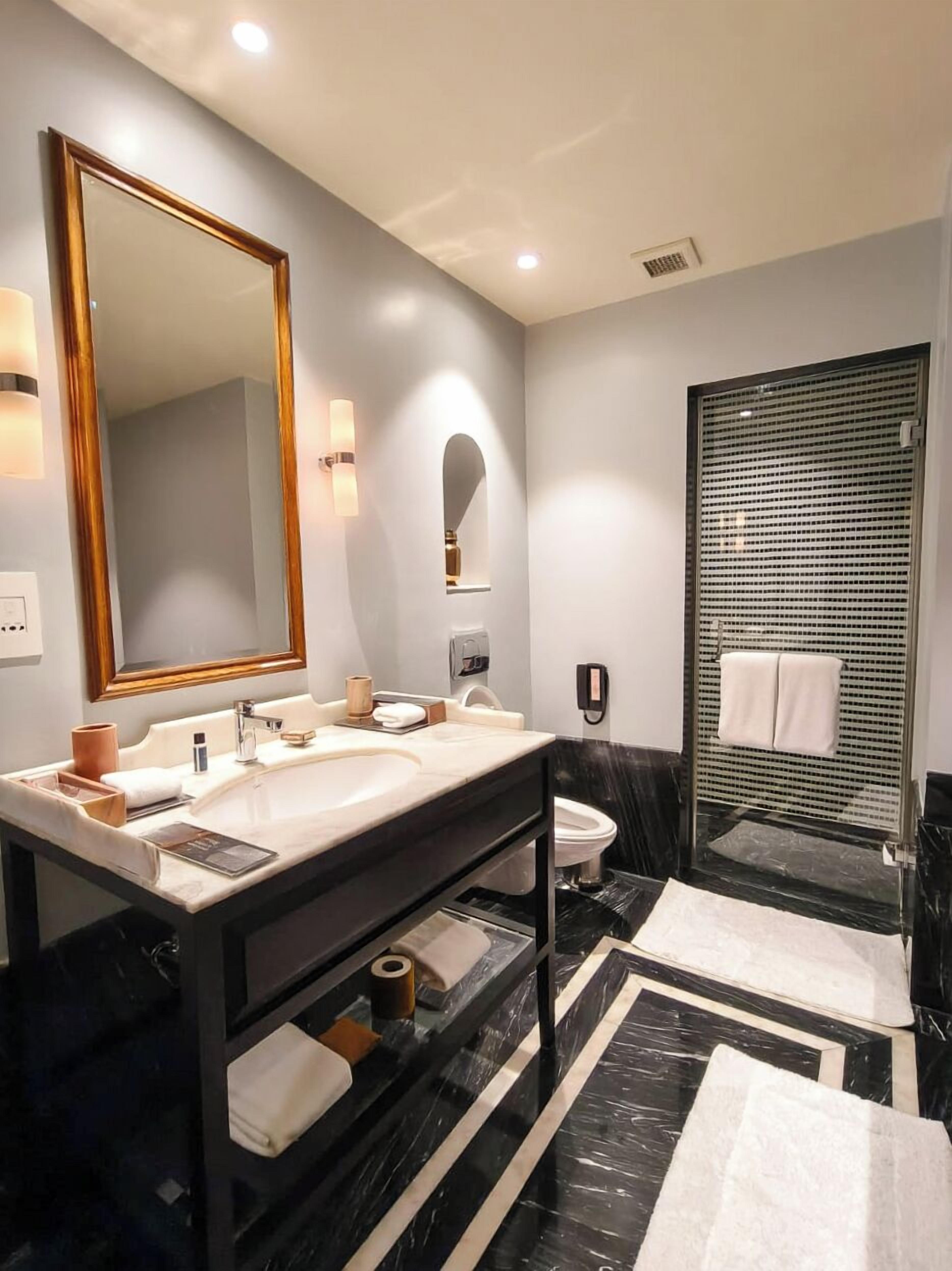 A modern bathroom with two sinks, a large mirror, a shower enclosure, and a marble floor.