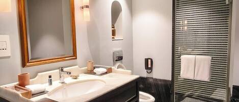 Une salle de bain moderne avec deux lavabos, un grand miroir, un espace douche et un sol en marbre.