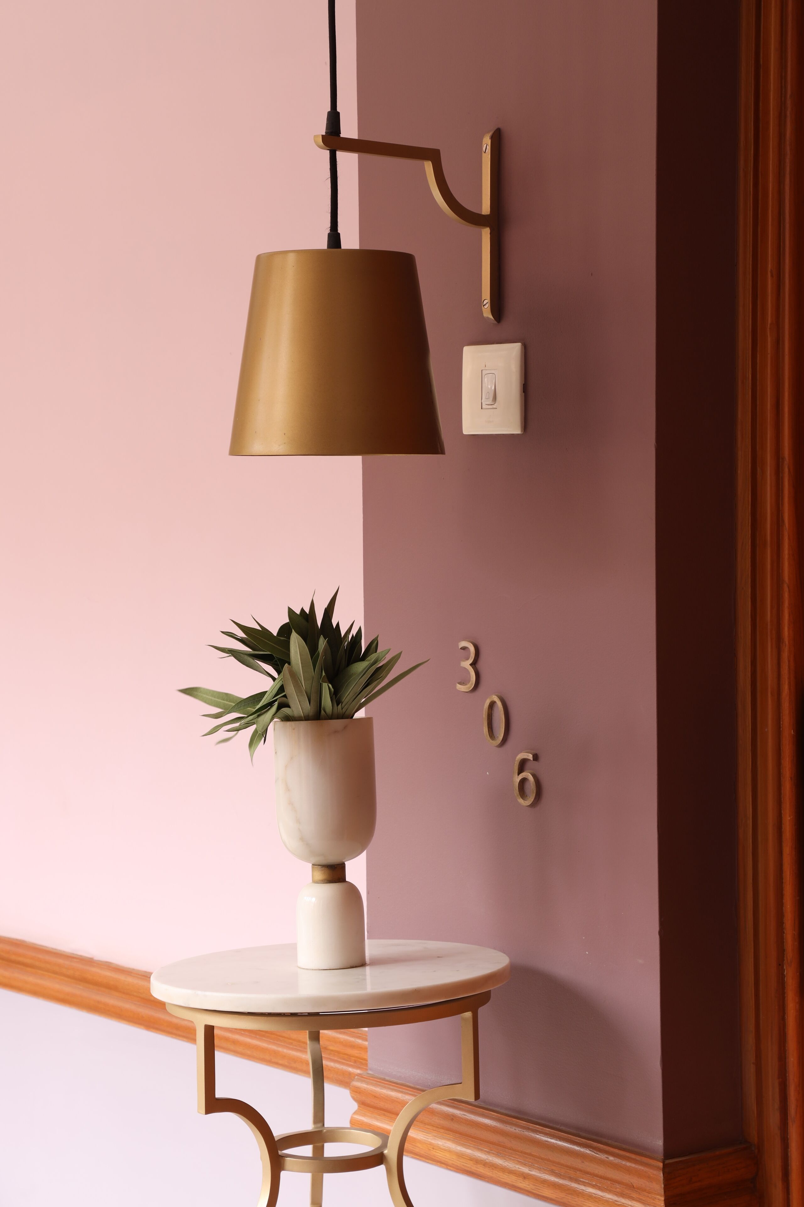 Una lámpara de pared, una planta en maceta y una pared con números.