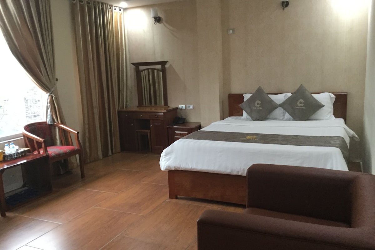 A hotel room with a bed, a desk, a chair, and a window with curtains.