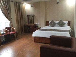 A hotel room with a bed, a desk, a chair, and a window with curtains. - Chio Hotel and Apartment (Hanoi)