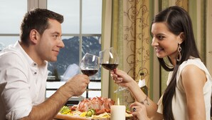 A couple dining at a table with a mountain view, enjoying wine and a charcuterie board. - Alpenhof Waengle (Waengle)