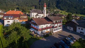 A town with a prominent church featuring a red dome and a clock tower, surrounded by residential buildings and a mountainous backdrop. - Alpenhof Waengle (Waengle)