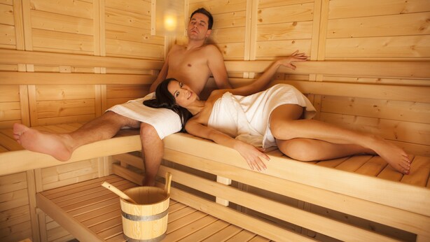A wooden sauna with two people lying on benches. - Alpenhof Waengle (Waengle)