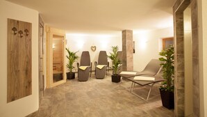 A modern interior with two reclining chairs, a small table, and potted plants. - Alpenhof Waengle (Waengle)
