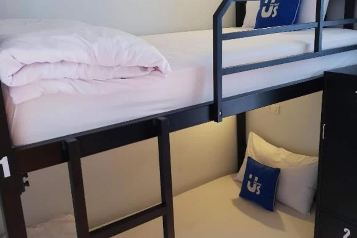 Une chambre avec un lit superposé, un bureau et un petit placard.