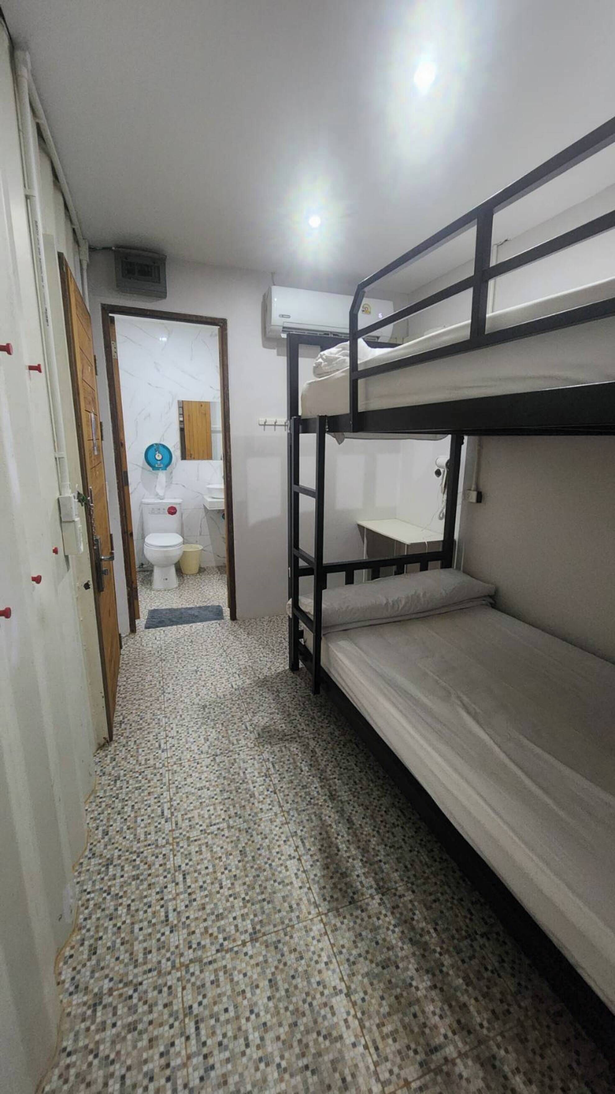 A narrow hallway with a bunk bed, a toilet, and a sink.