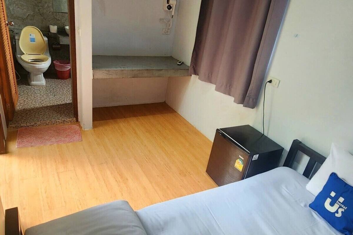 Une chambre avec un lit, un petit bureau, une salle de bain avec des toilettes et une douche.