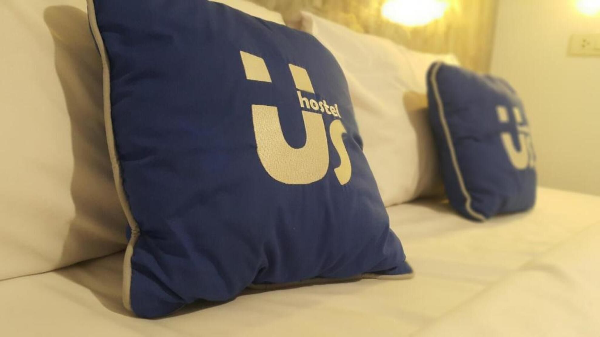 Dos almohadas con el logotipo del Hostel sobre una cama.