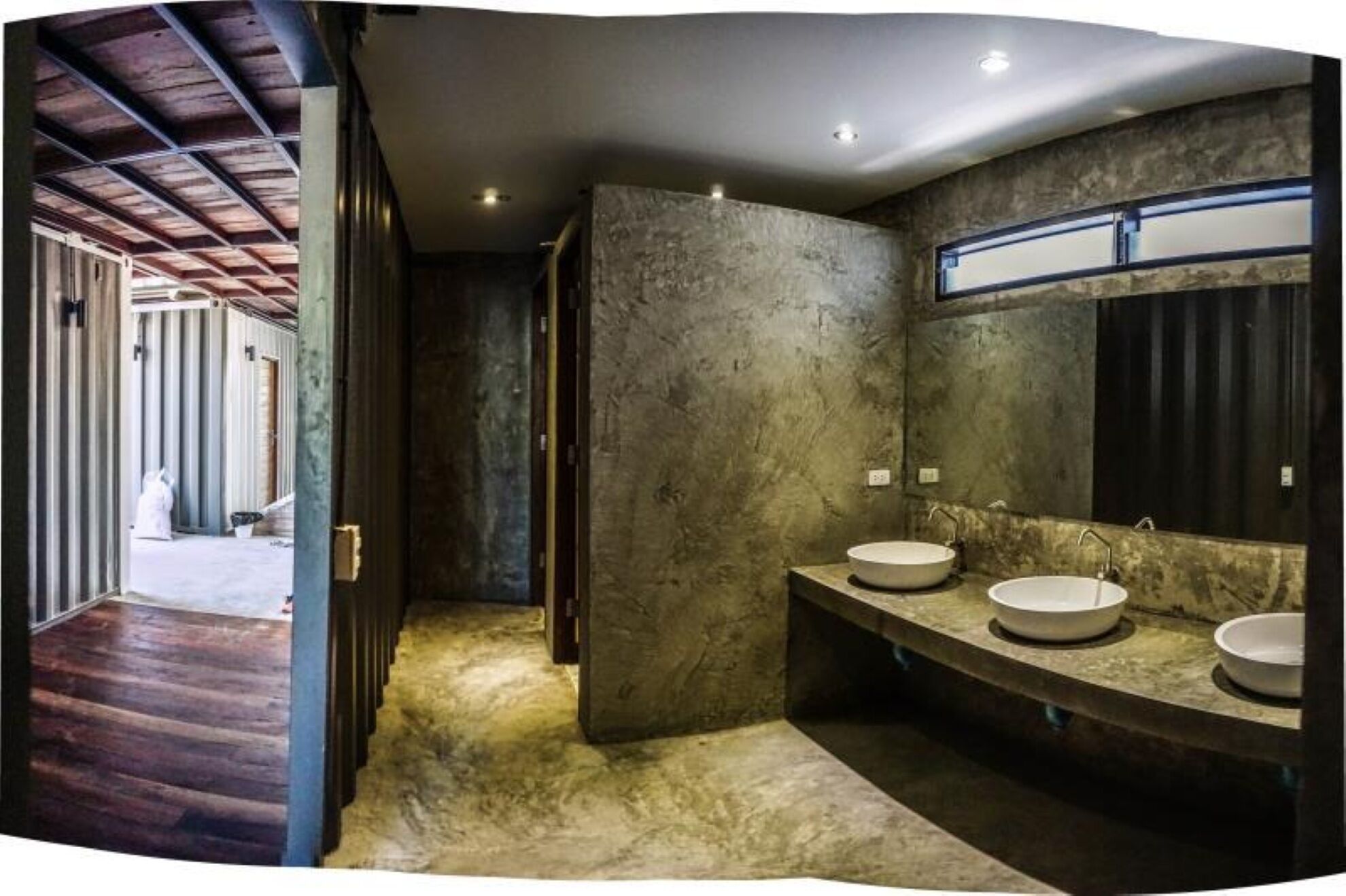 Un baño con un espejo grande, dos lavamanos y una pared con textura.