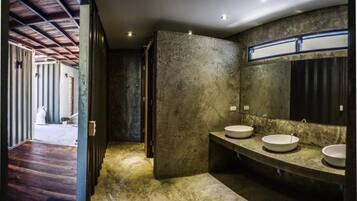 Un baño con un espejo grande, dos lavamanos y una pared con textura.