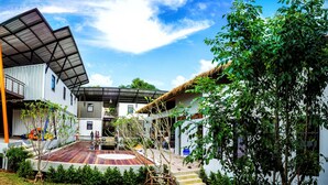 A modern house with a flat roof, a balcony, and a wooden deck. - Us Hostel Samui (Koh Samui)