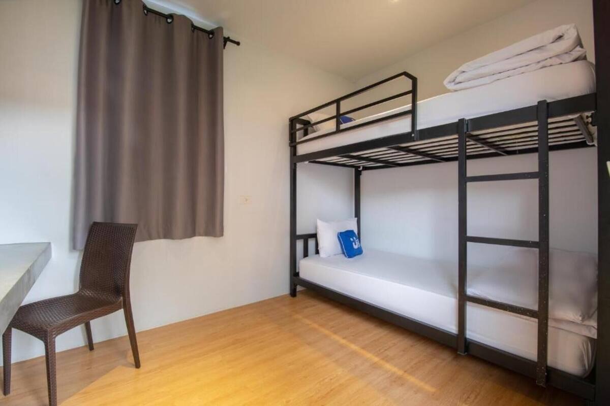 Une chambre avec un lit superposé, une chaise et une table.