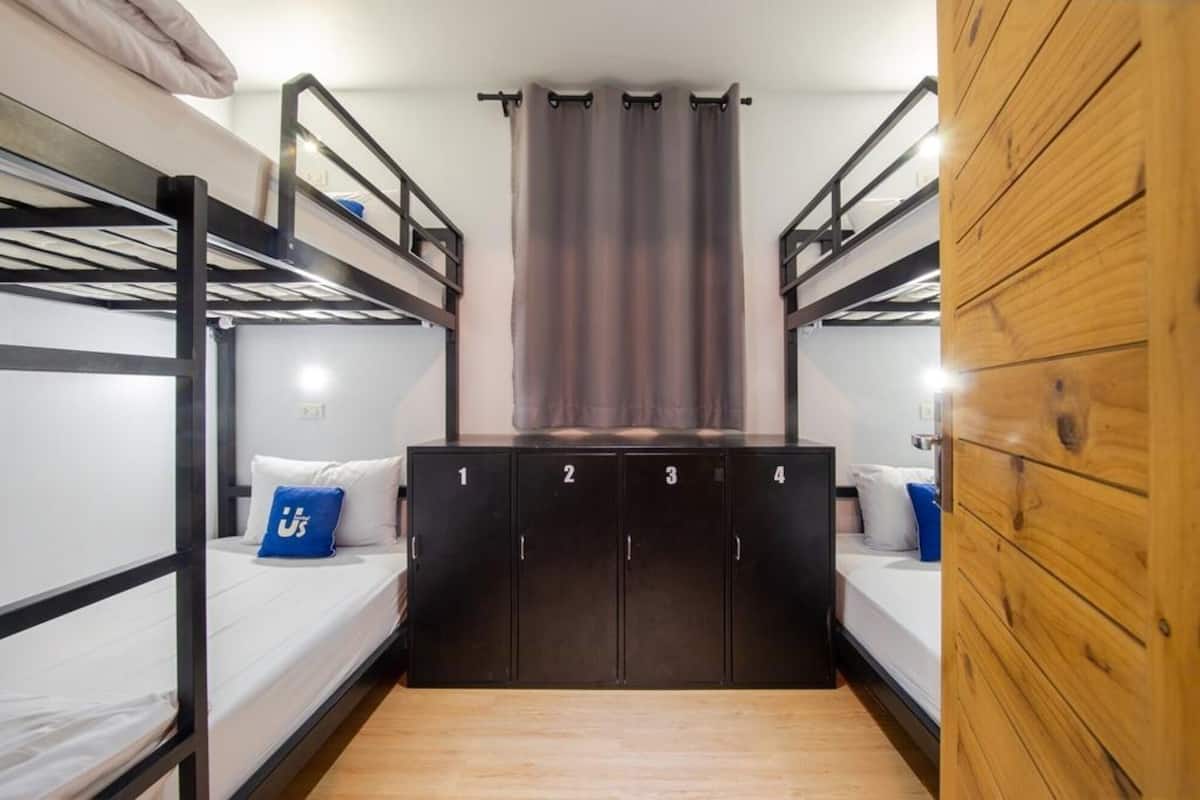 Une chambre de dortoir avec des lits superposés, une armoire centrale et un mur recouvert de panneaux de bois.
