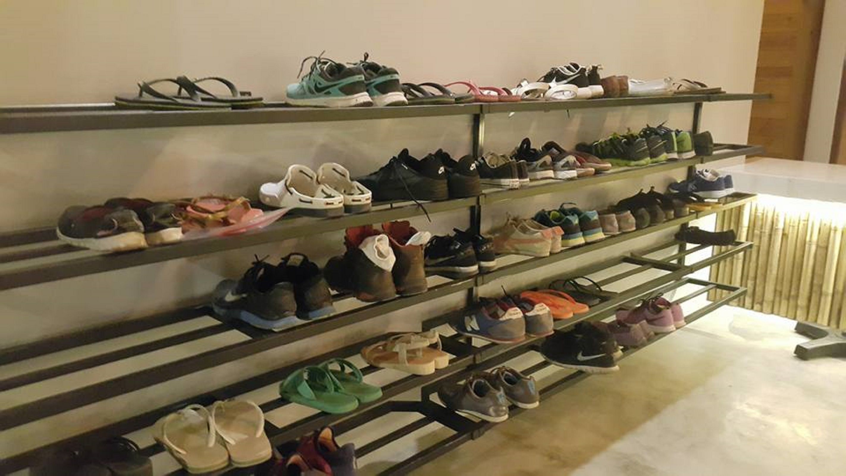A shoe rack with multiple shelves holding various pairs of shoes.