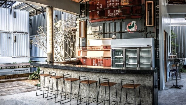 A bar area with a high ceiling, exposed beams, and a rustic aesthetic. - Us Hostel Samui (Koh Samui)