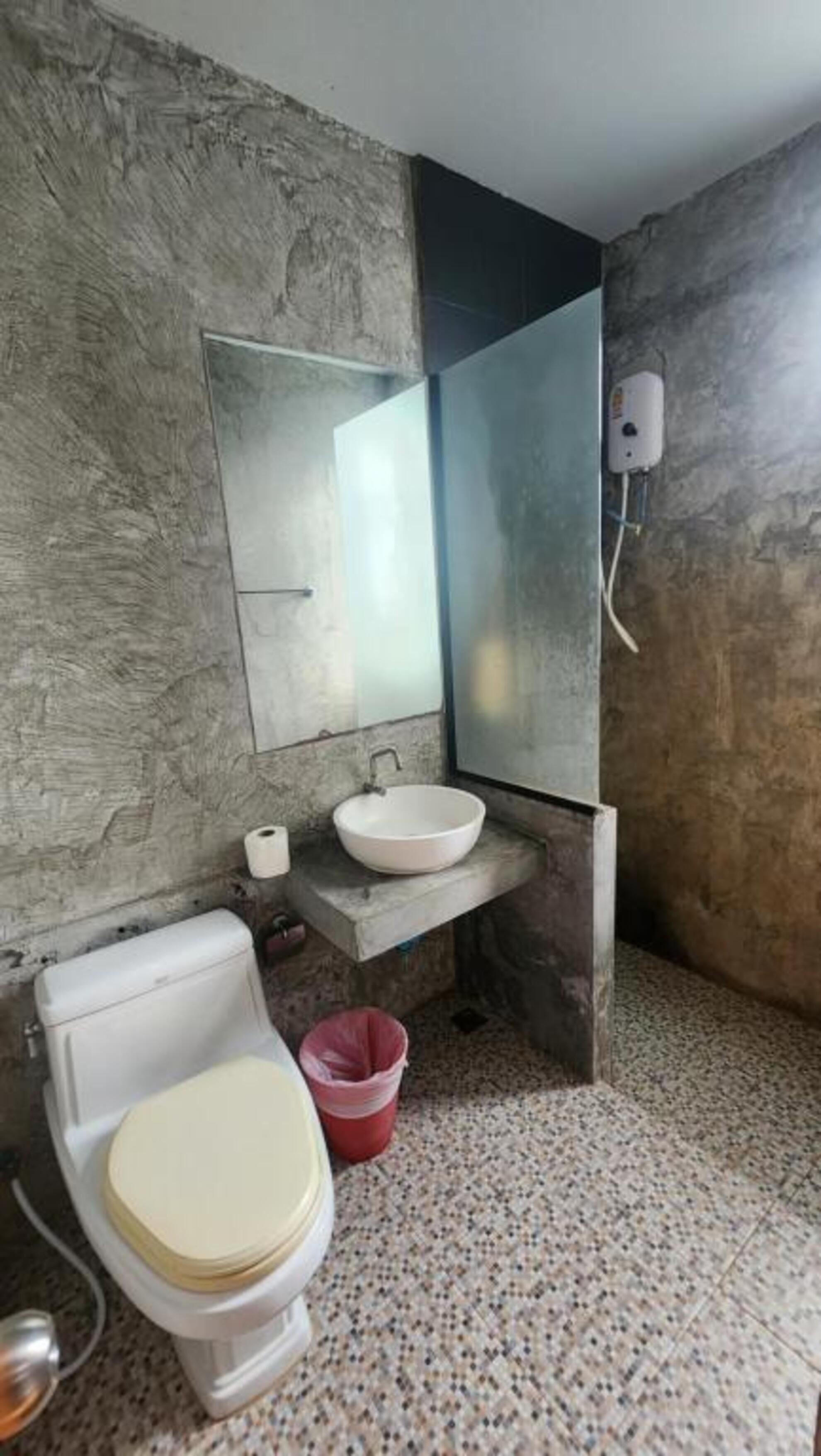 A bathroom with a toilet, sink, and mirror.