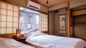 A traditional Japanese-style room with two beds, a sliding door, and a view of the outside balcony. - Rin Kyoto (Kyoto)
