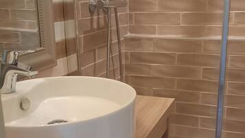 A bathroom with a white sink, a mirror, and a shower.
