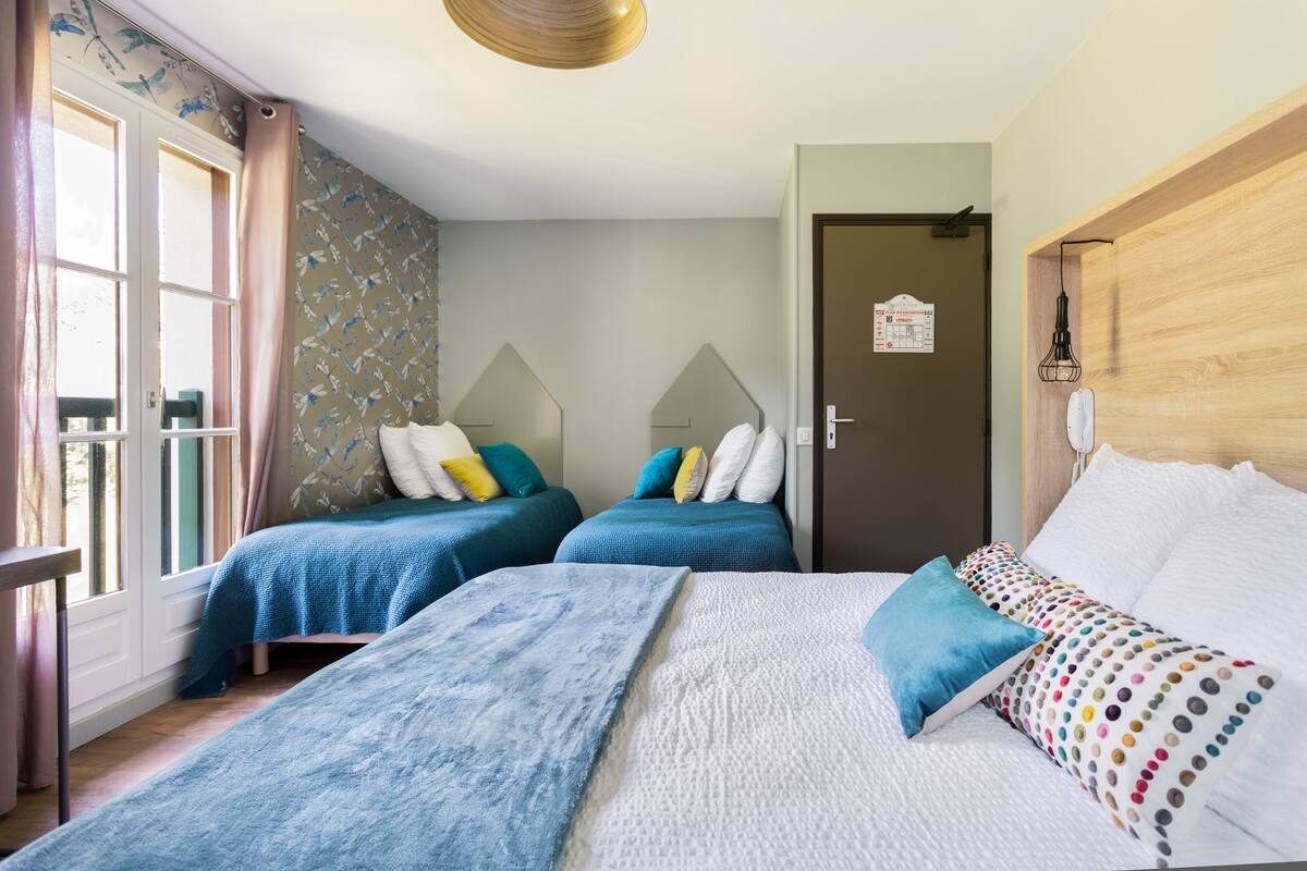 Ein Hotelzimmer mit zwei Betten, einem Holzkopfstück, einer Wand mit Muster und einer Tür mit einem Schild.