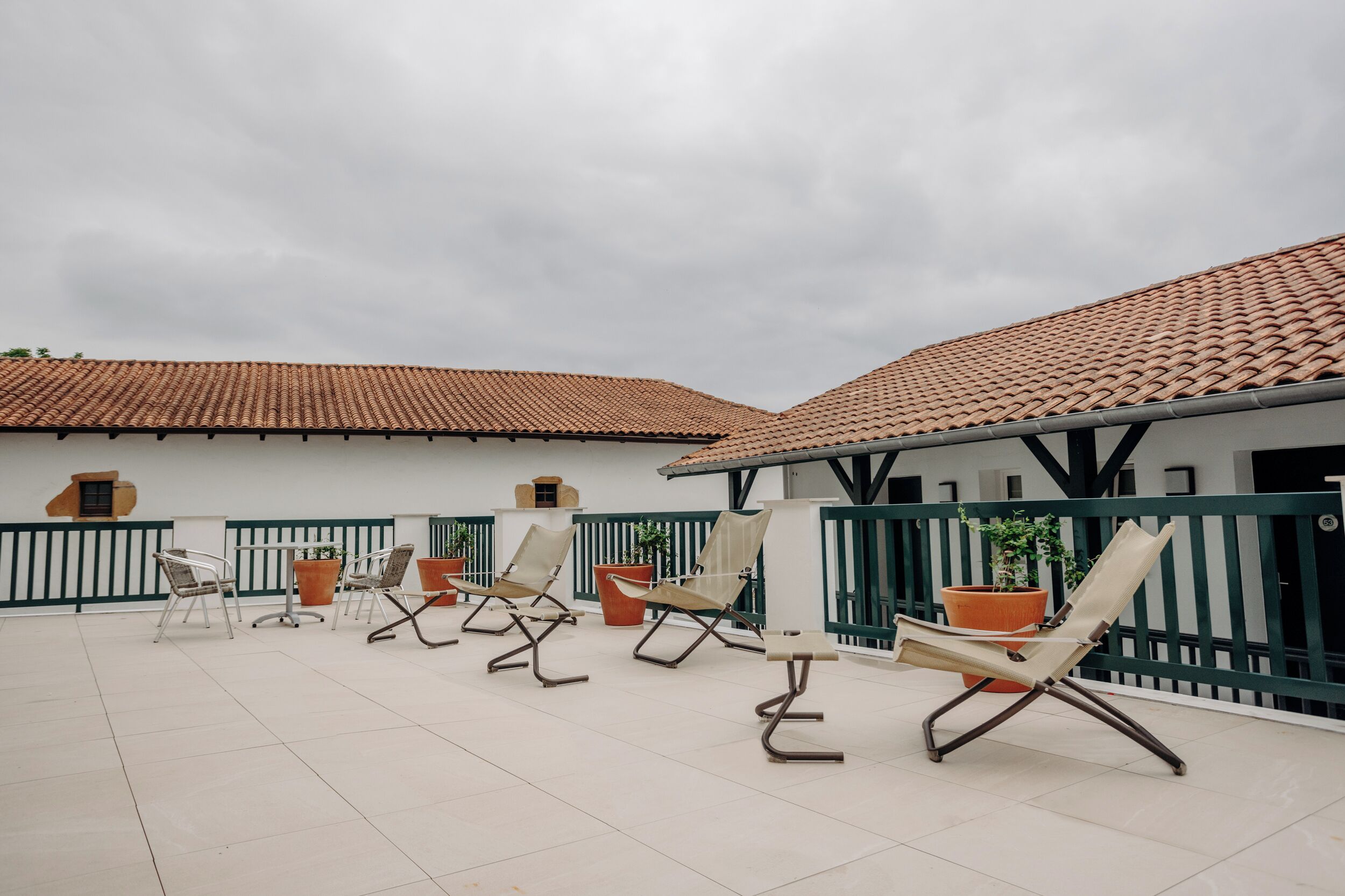 A covered outdoor seating area with lounge chairs and potted plants.
