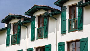 Un edificio con varias ventanas, contraventanas verdes y tejado de tejas.