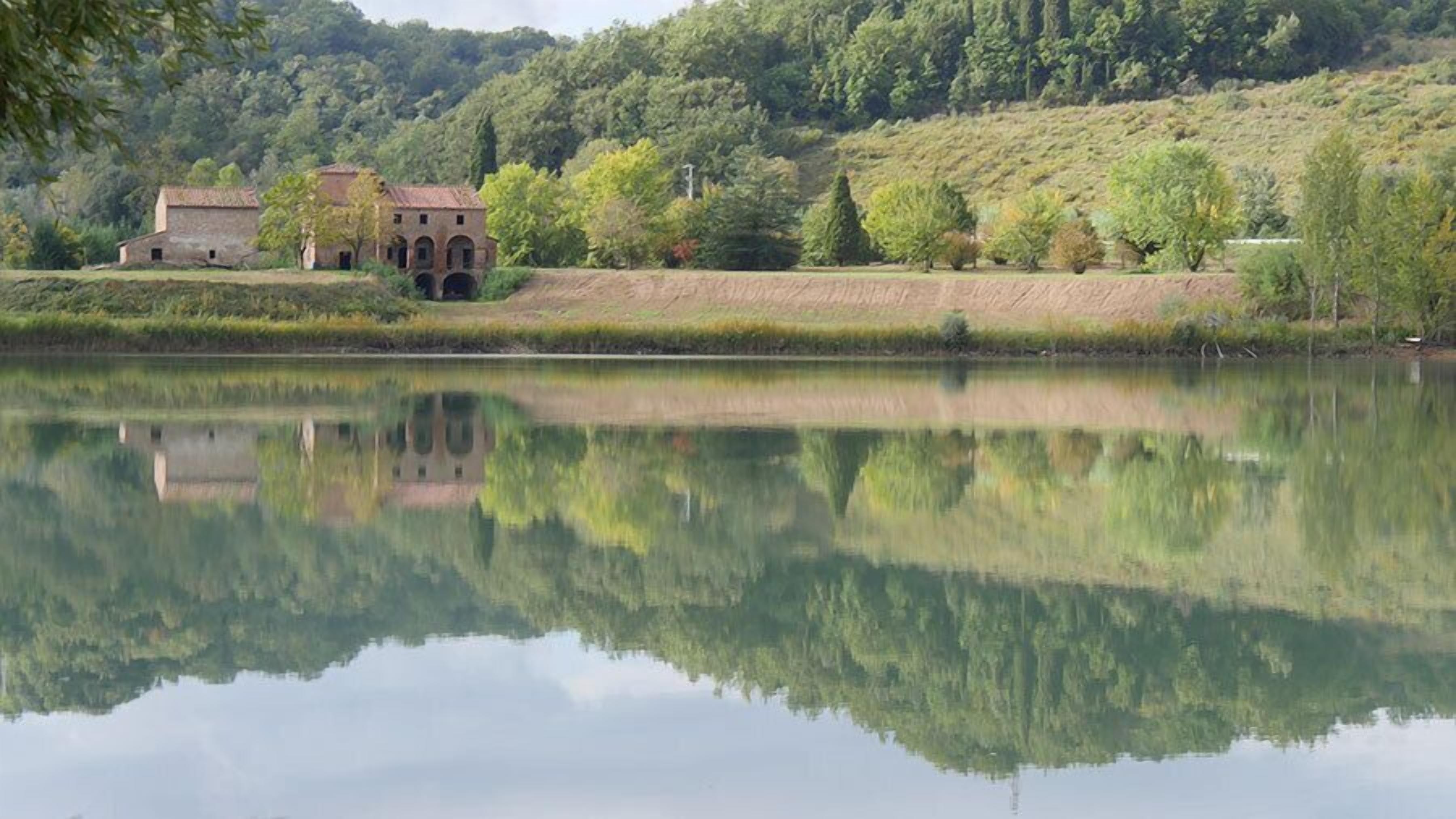 A serene lake with a reflection of a historic building and trees.