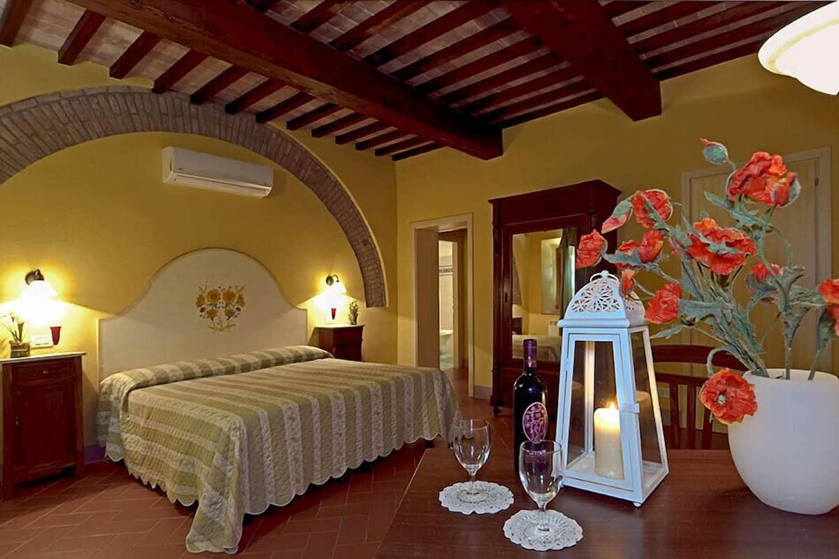 Une chambre à coucher avec un lit, des lampes de chevet, une table de chevet, un vase avec des fleurs, une bouteille et une lanterne.