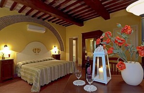 Una camera da letto con un letto, lampade da comodino, un tavolino, un vaso con fiori, una bottiglia e una lanterna.