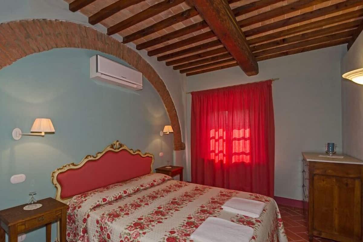 Une chambre à coucher avec un lit, une table de chevet, une armoire en bois et un rideau rouge.