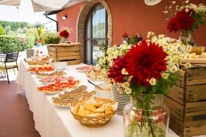 Una mesa preparada con diferentes alimentos y flores, lo que sugiere un montaje para comer o un evento.