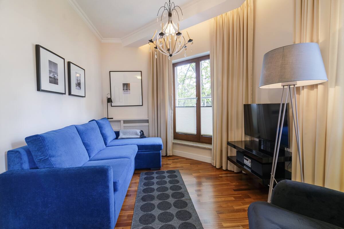 Una sala de estar moderna con un sofá azul, un televisor y una araña.