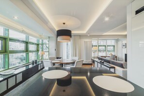 Un salon moderne avec une table ronde, un canapé et une grande fenêtre aux montures vertes.