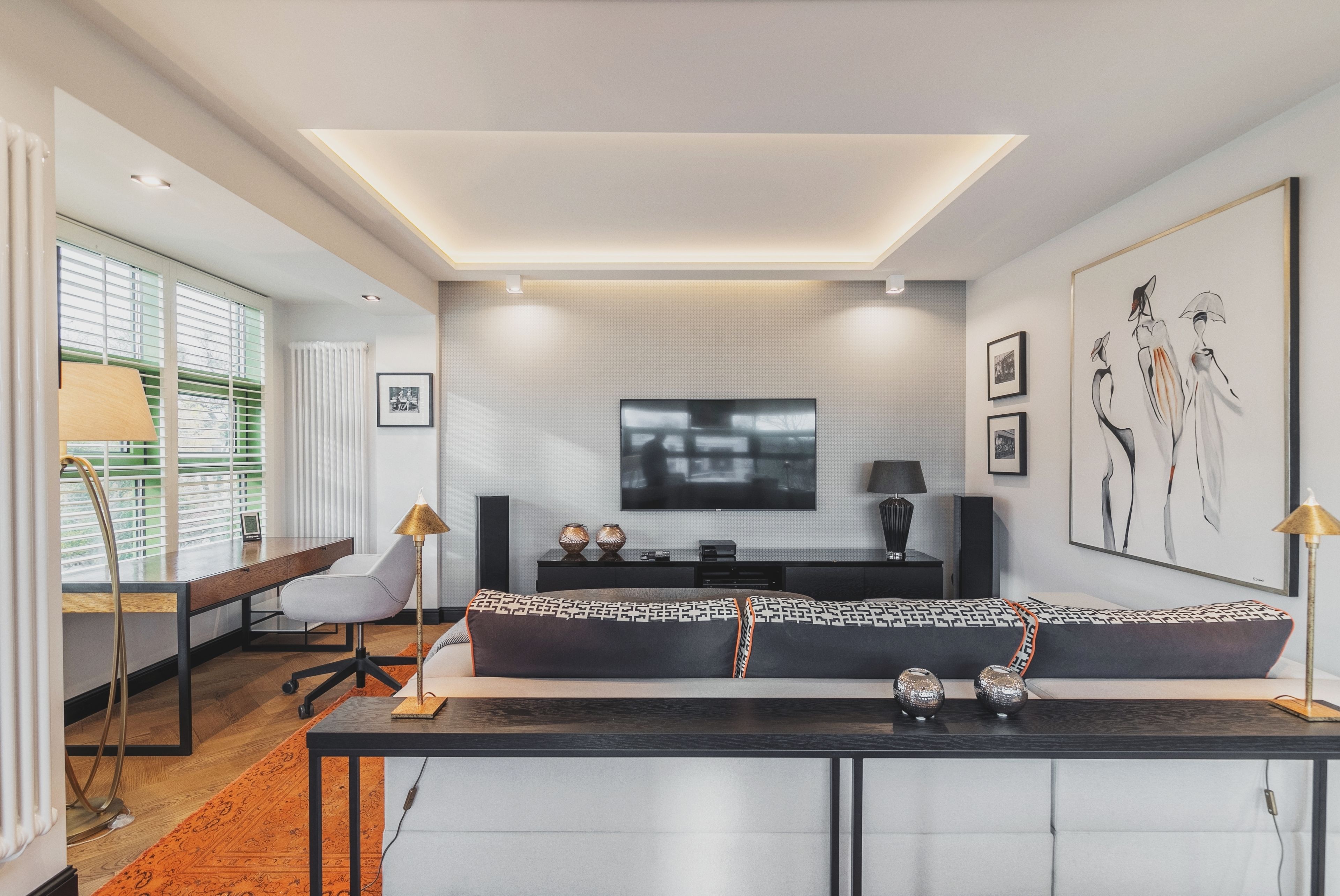 Una sala de estar moderna con un sofá, televisión y obras de arte en la pared.