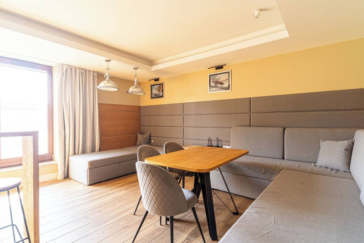 Una sala moderna con una mesa de comedor de madera, un sofá gris y un banco acolchado.