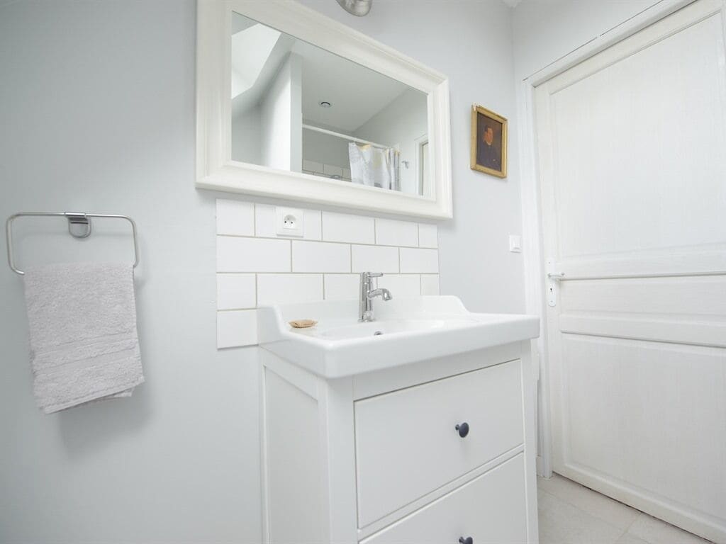 A bathroom with a white sink, a mirror, a towel rack, and a door.