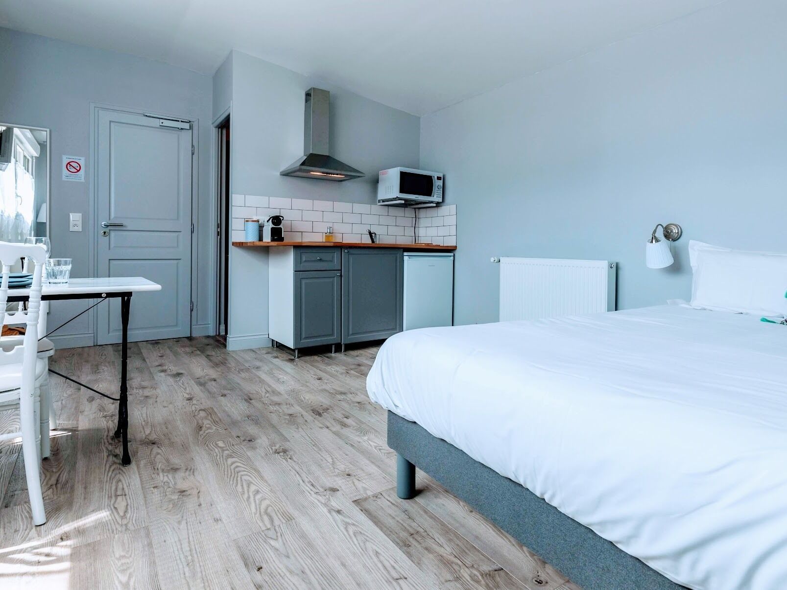 Una camera d'albergo compatta con un letto, un angolo cottura, un tavolo e una sedia.