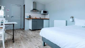 Una camera d'albergo compatta con un letto, un angolo cottura, un tavolo e una sedia.