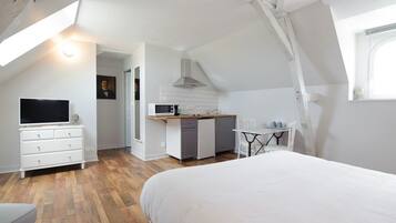 Une chambre dotée d’un grand lit, d’une télévision, d’une kitchenette et d’un coin repas.
