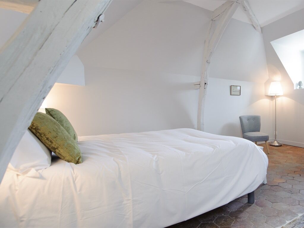 A bedroom with a bed, a chair, a lamp, and a hexagonal floor pattern.