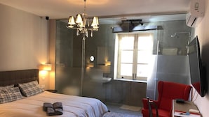 A hotel room with a bed, a red chair, a TV, a shower, and a window. - Lee's House Bed & Breakfast Sliema (Sliema)