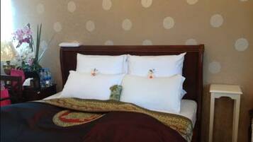 A neatly made bed with a dark red blanket and a decorative pillow.