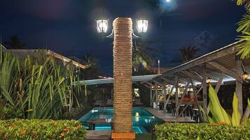 Relax by the pool surrounded by lush greenery under a shaded pergola.