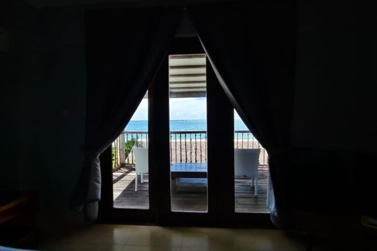 A room with a view of a beach through large windows.