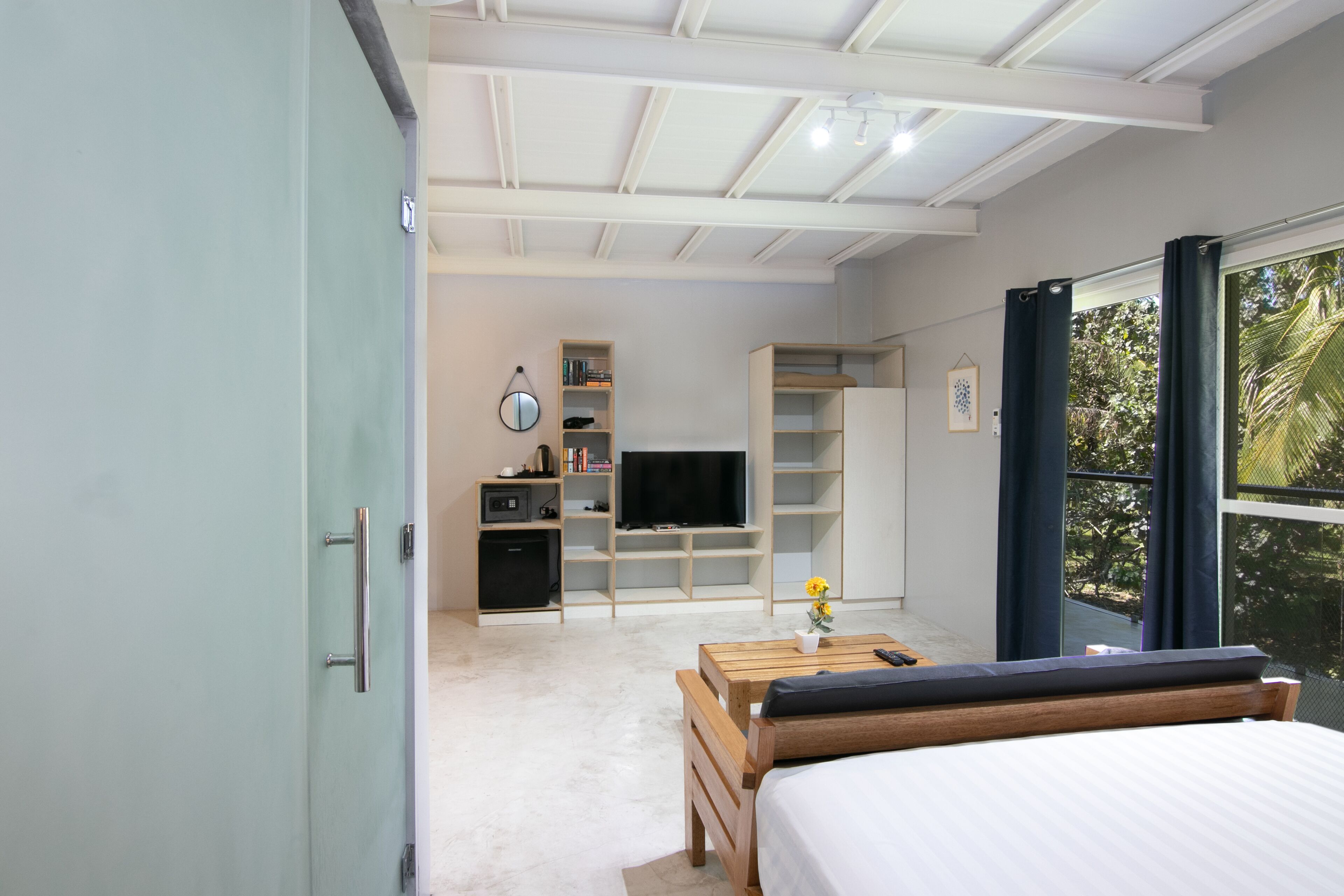 Une chambre moderne avec un lit, un bureau, une télévision et une bibliothèque.