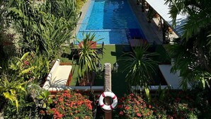 A pool area with a view of the ocean, surrounded by palm trees and lounge chairs. - Reef Beach Resort (General Luna)
